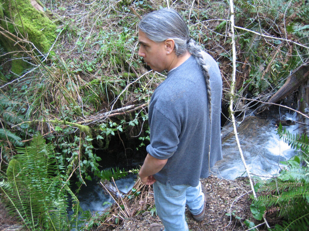 a man pauses in front of a small creek