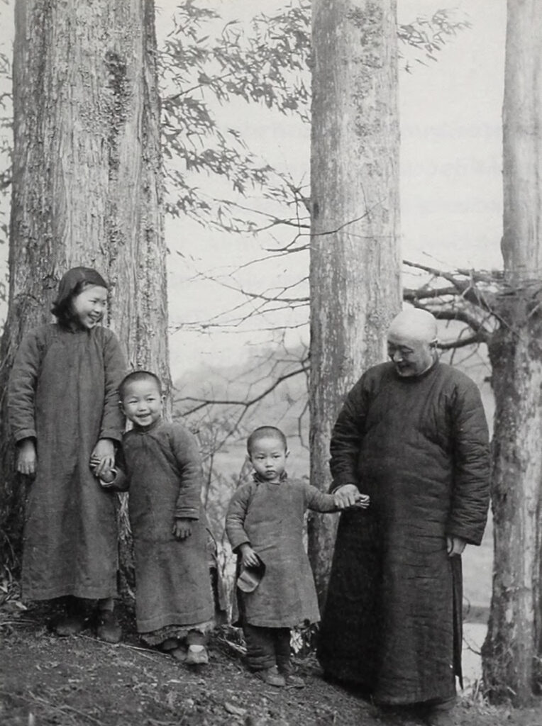 black and white photo of a family dressed in traditional Chinese tunics posing in front of three trees