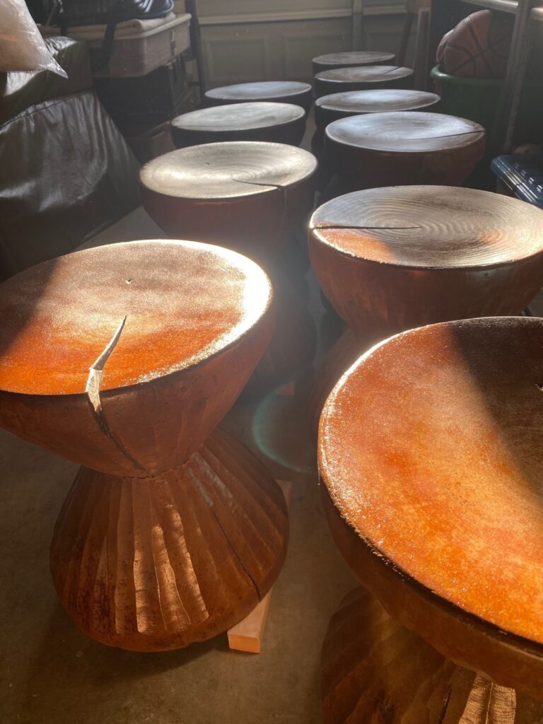 hourglass-shaped stools made of wood sit in a room with the sunlight hitting them