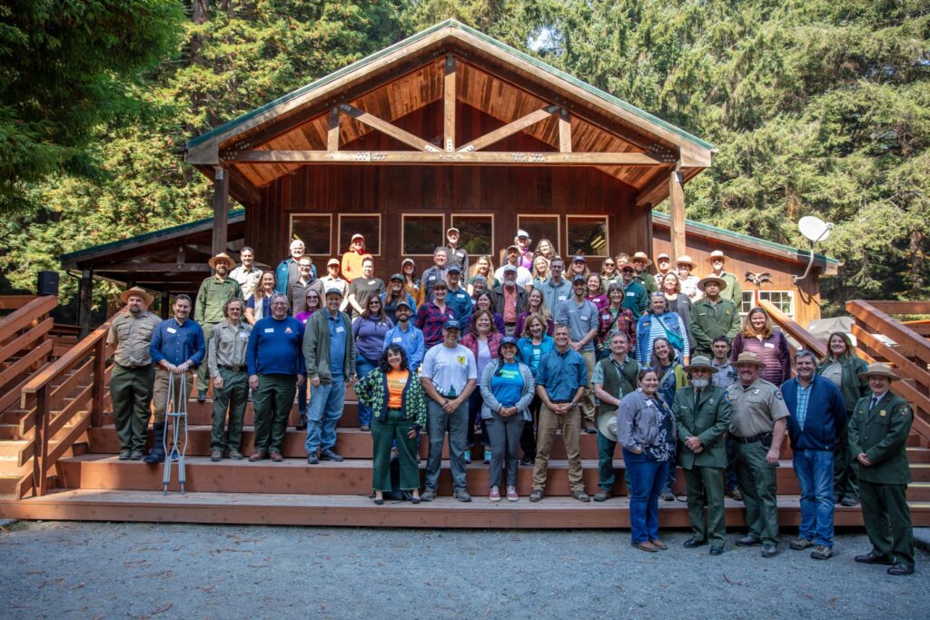 A group of people ose in front of a cabin-like structure