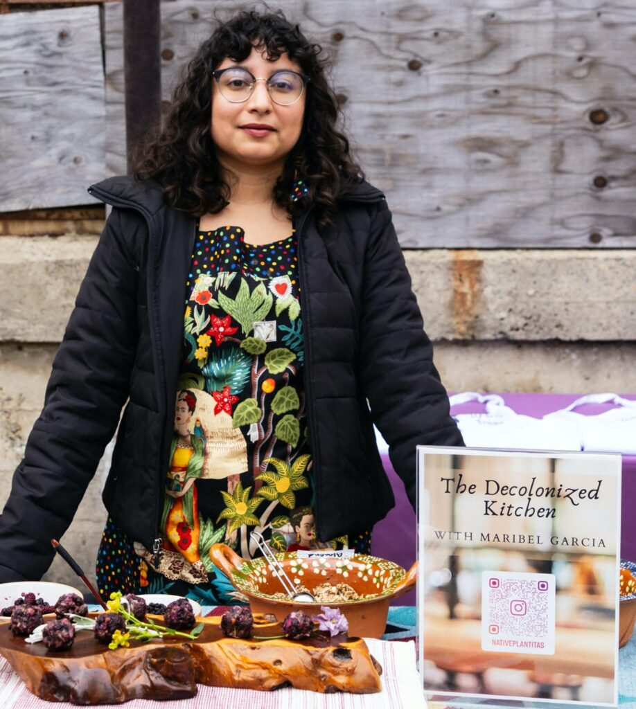 A woman stands in front of a table of foods on different platters