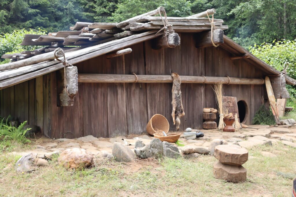 A traditional Yurok house made of redwood planks with a low circular door to one side