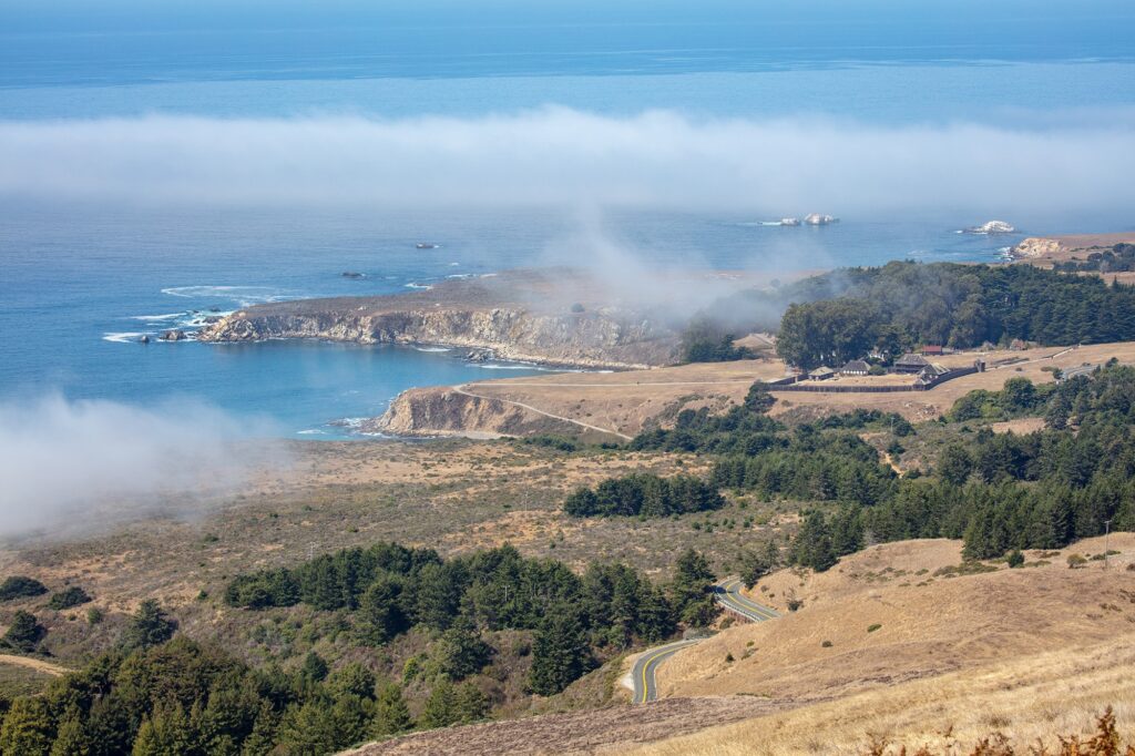 The view from the top, overlooks a fantastic ocean, cliffs, and trees with fog rolling in.