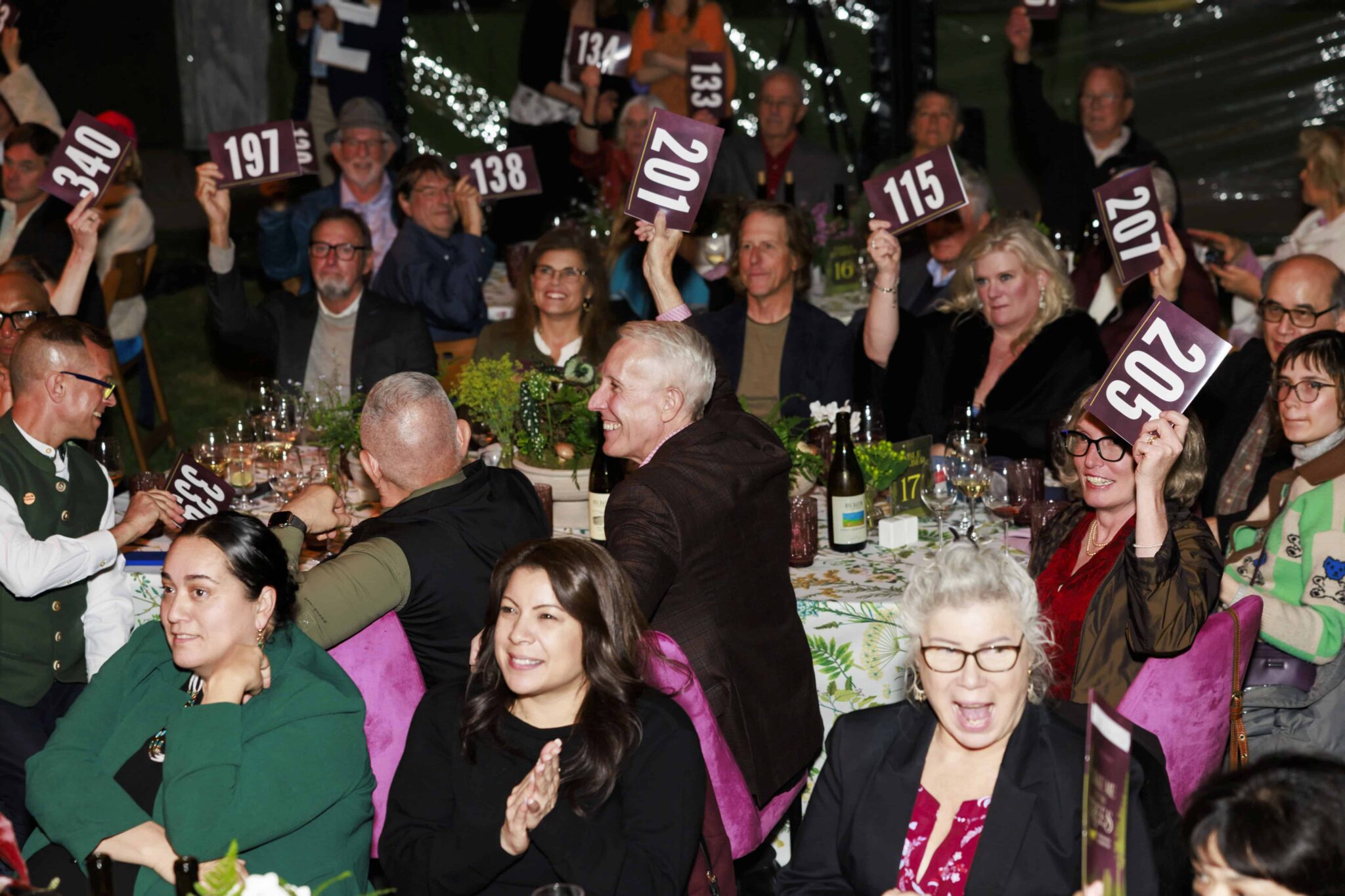 Partygoers bidding in an auction with several holding up paddles