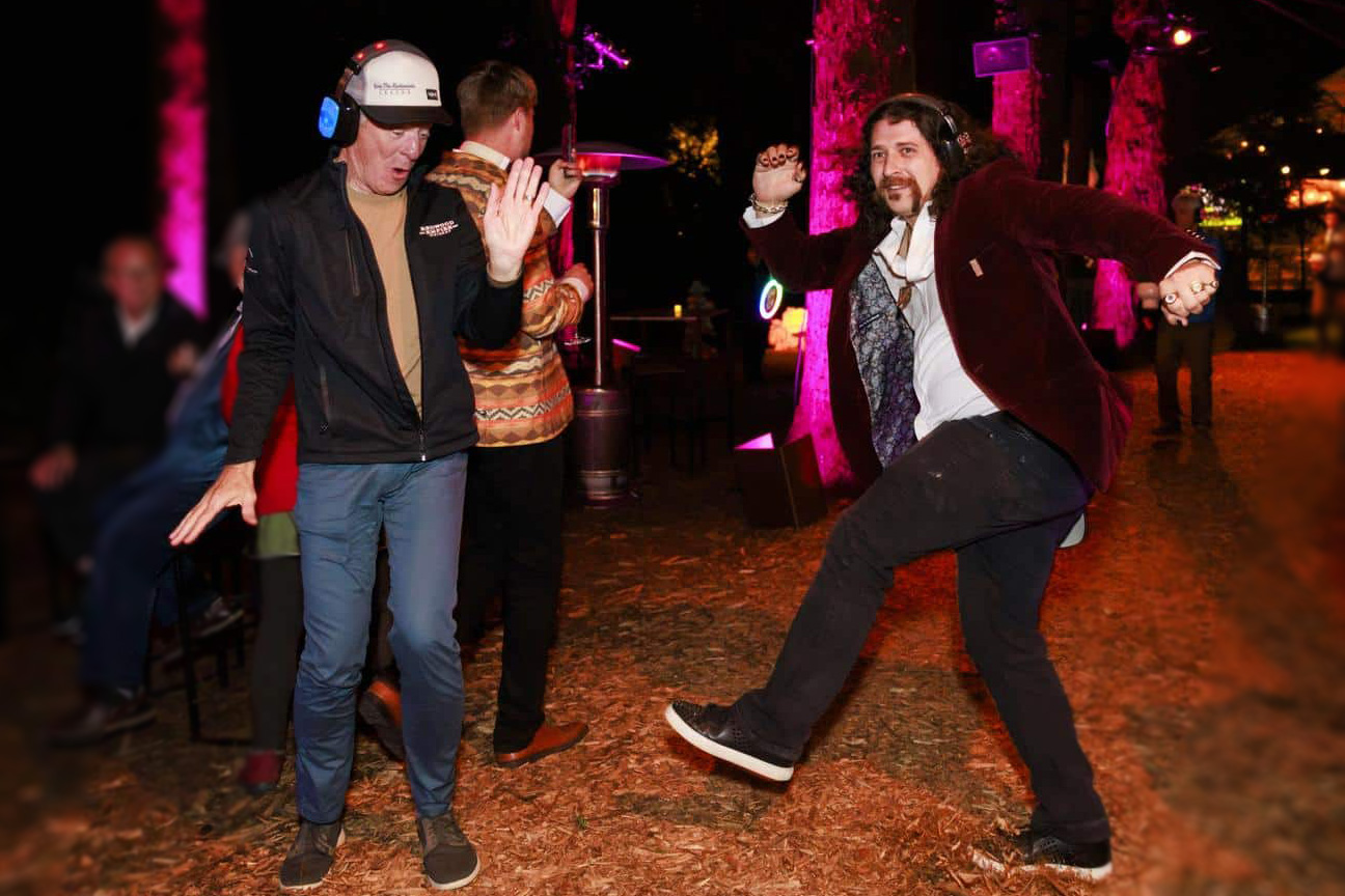 Two guests wearing headphones and dancing to silent disco in a redwoods grove.