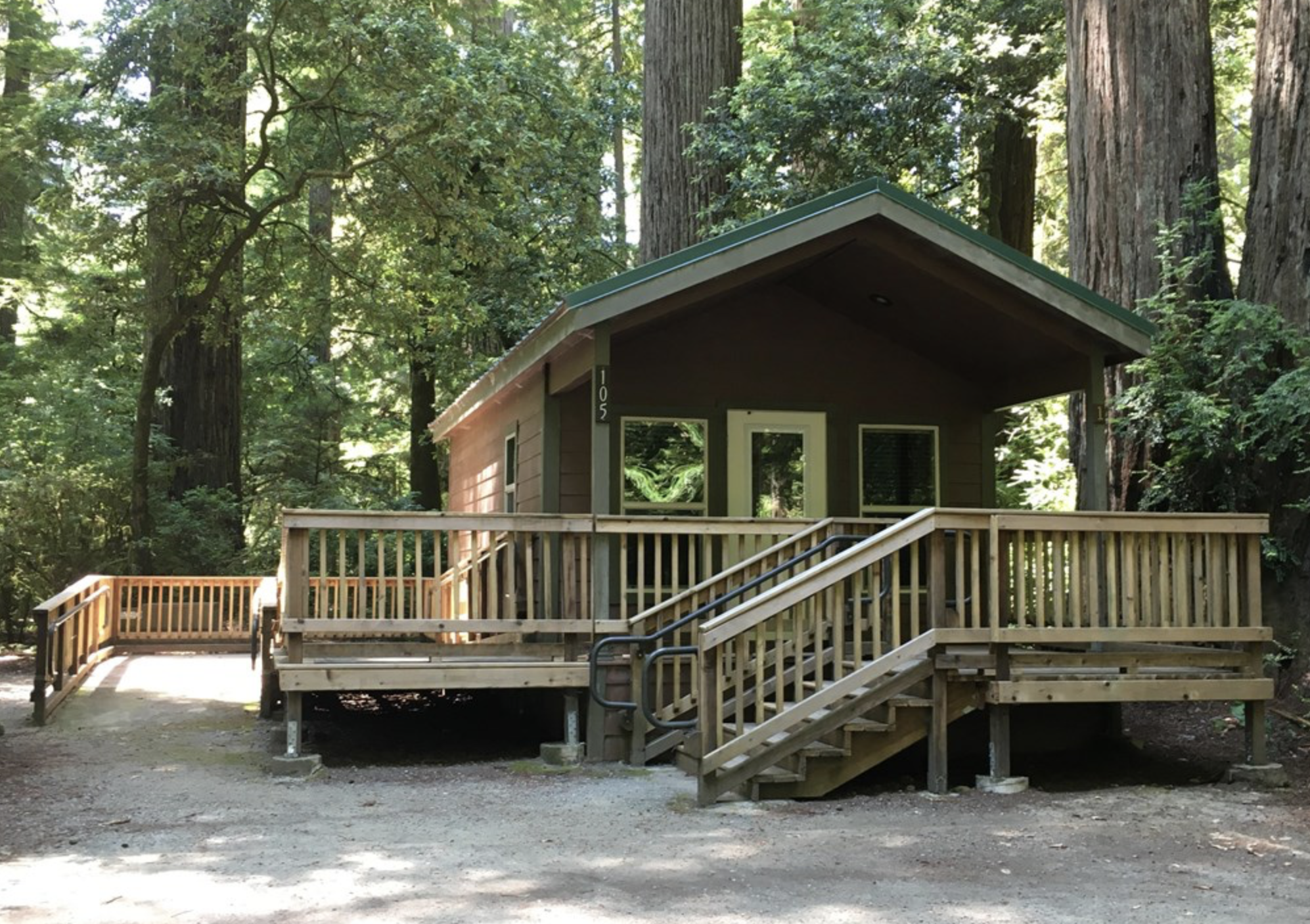 Stairs leading up to a dark brown cabin with a green roof