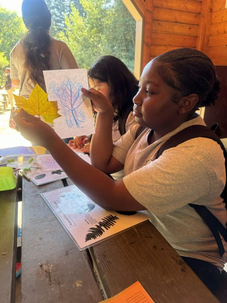Student showing leaf rubbing art project