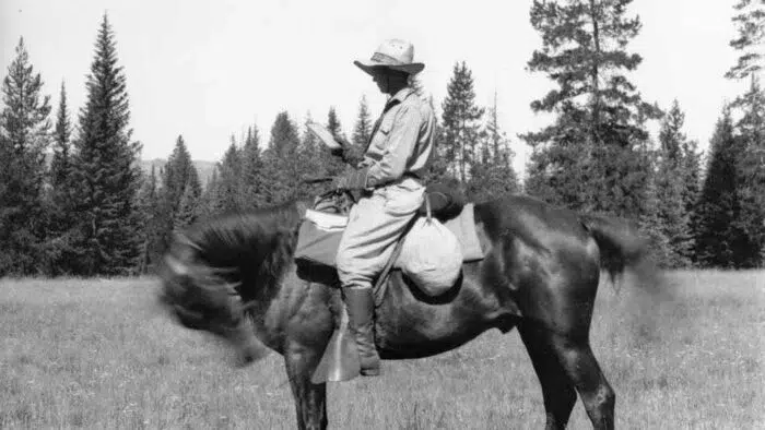 black and white photo of a woman on horseback wearing a wide-brimmed hat