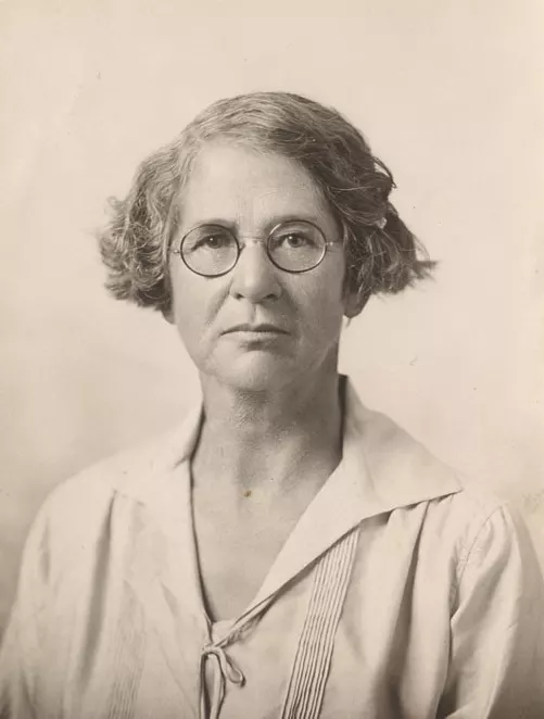 a sepia-tinted portrait of a woman with round glasses and short hair